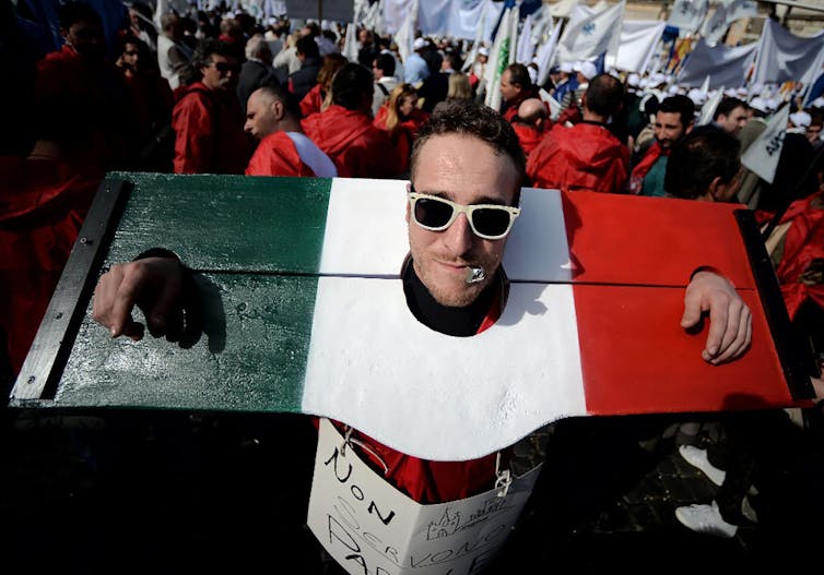 Un manifestant attachait à un pilori aux couleurs du drapeau italien lors d’une manifestation pour demander au gouvernement des réformes suite à la crise économique